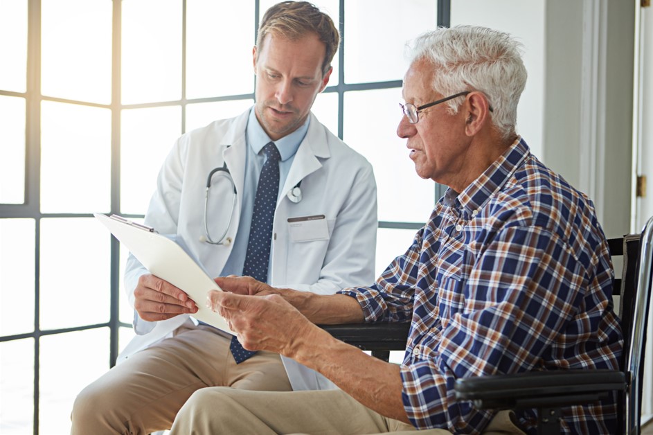 Médico urologista em seu consultório explicando para seu paciente, homem por volta dos 70 anos, sobre o tamanho normal da próstata.