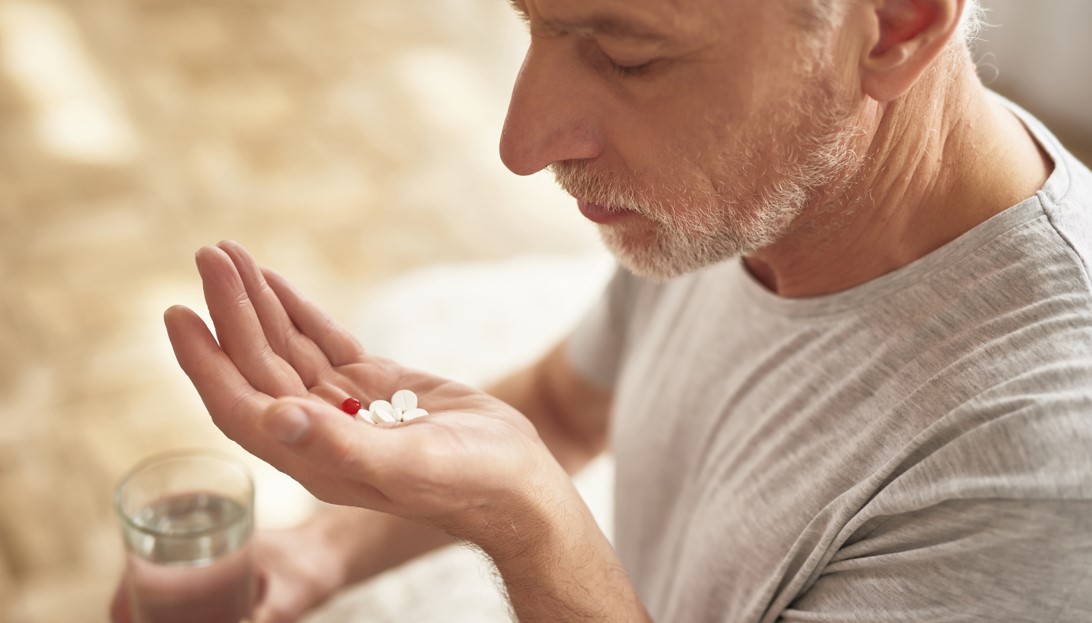 Homem tomando o remédio Combodart® e se questionando para que serve a medicação.