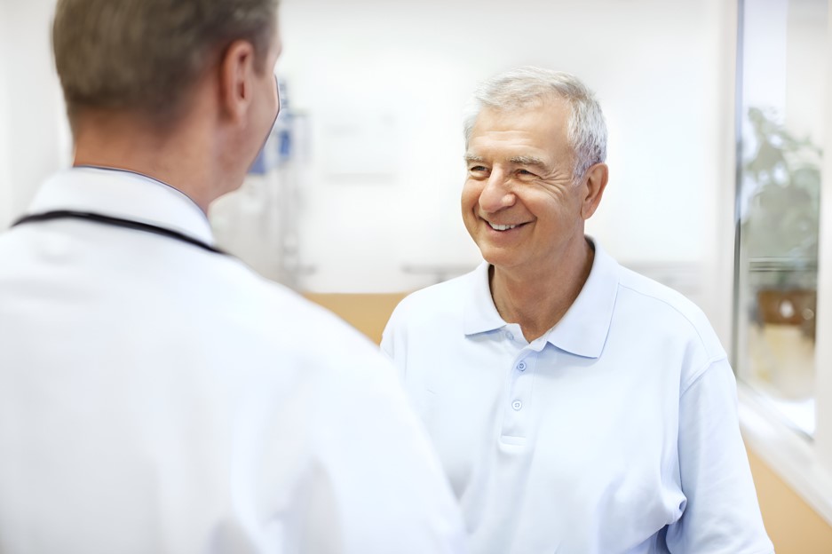 Médico urologista mostrando para seu paciente mais velho, homem por volta dos 70 anos, qual é o volume da próstata normal para tal idade.