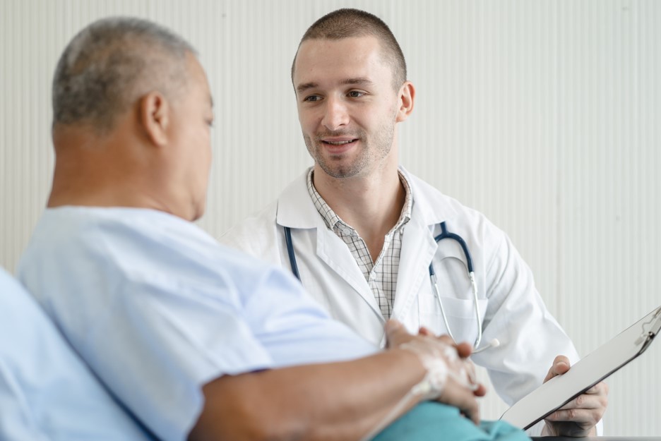 Médico urologista conversando com seu paciente, homem por volta dos 50 anos, sobre o câncer no rim.