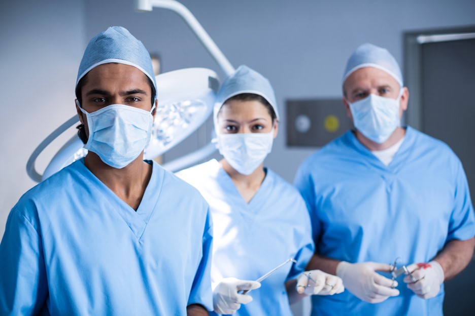 Médicos especializados em endourologia em uma sala cirúrgica pousando para uma foto.