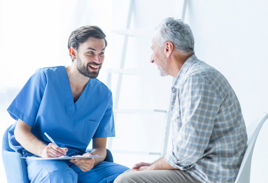 Médico urologista em seu consultório explicando para seu paciente, homem por volta dos 65 anos, sobre o procedimento ThuFLEP e seus benefícios para o tratamento da hiperplasia prostática benigna.