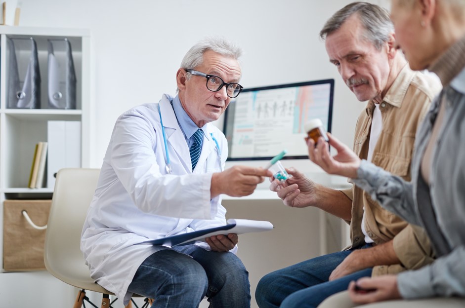 Médico urologista entregando remédios para diabetes e disfunção erétil para seu paciente, um homem mais velho por volta dos 65 anos.