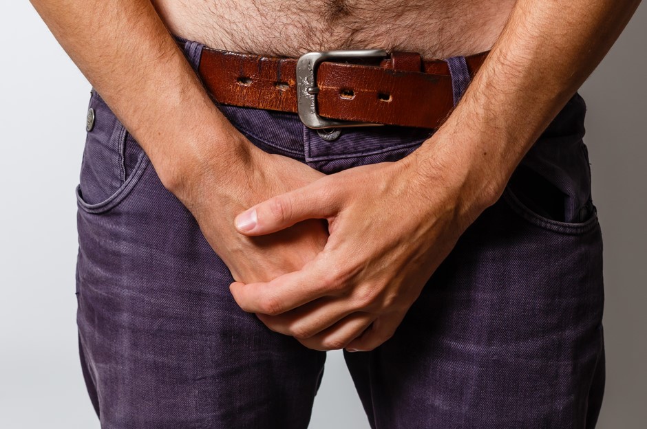 Homem segurando a região íntima achando que é uma forma de como aliviar infecção urinária imediatamente.