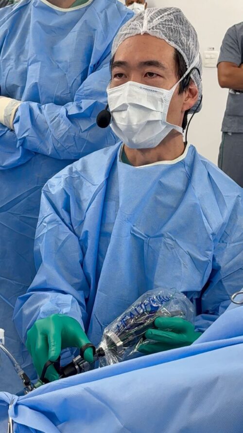 Médico realiza procedimento cirúrgico de urologia com equipamentos de proteção e instrumentos especializados, representando cirurgia HoLEP com tecnologia laser MOSES para tratamento da HPB.
