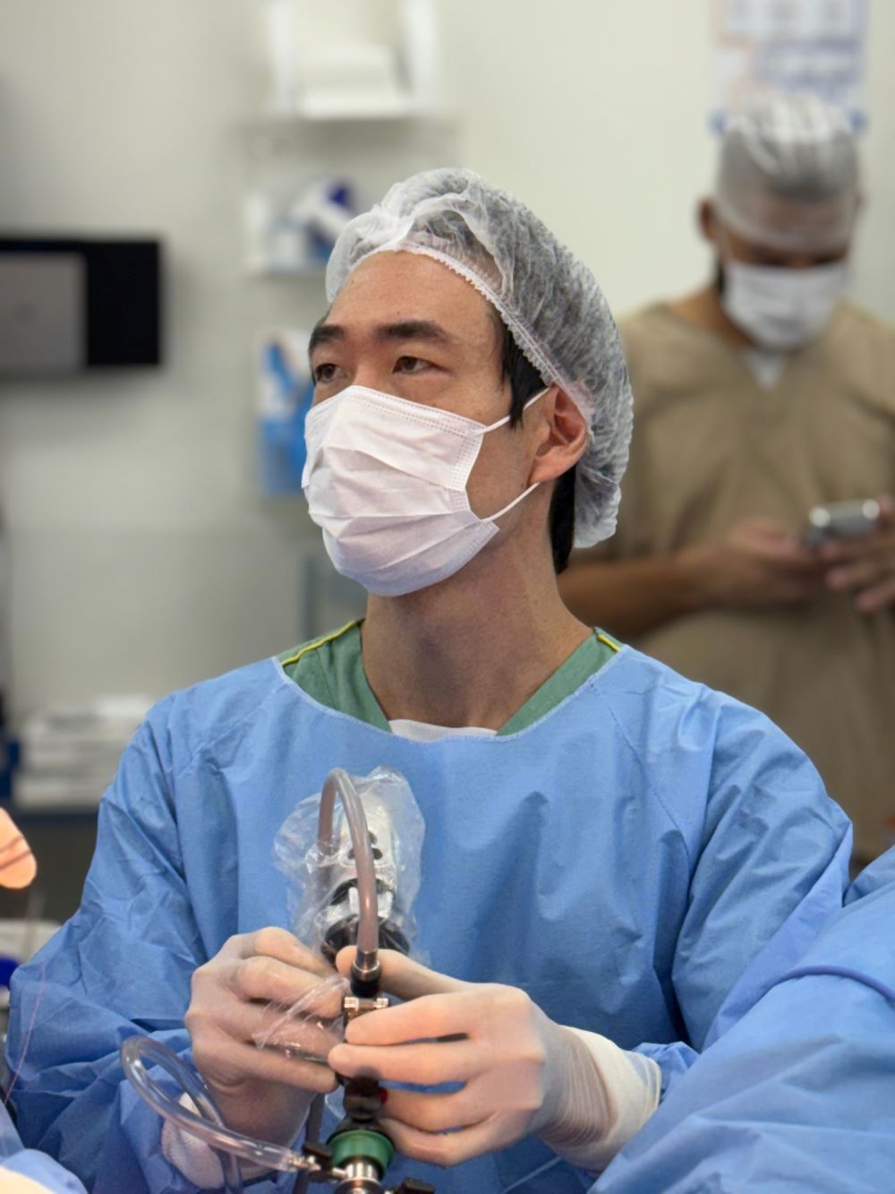 Dr. Jonathan Cha realiza procedimento de HoLEP com laser em ambiente cirúrgico, utilizando equipamentos de proteção e tecnologia urológica avançada.